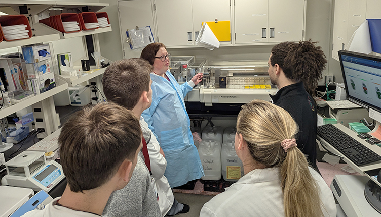 A Small group of medical students listen as the Renal Histology lab manager gives them a tour of during their Surgical Pathology rotation.