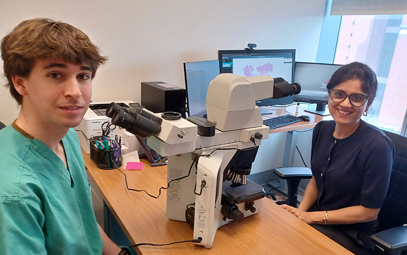 Dr. Vidya Arole (right) sits at microscope with student
