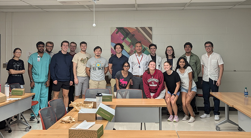 Dr. Gary Tozbikian and 16 medical students pose together for a photo.